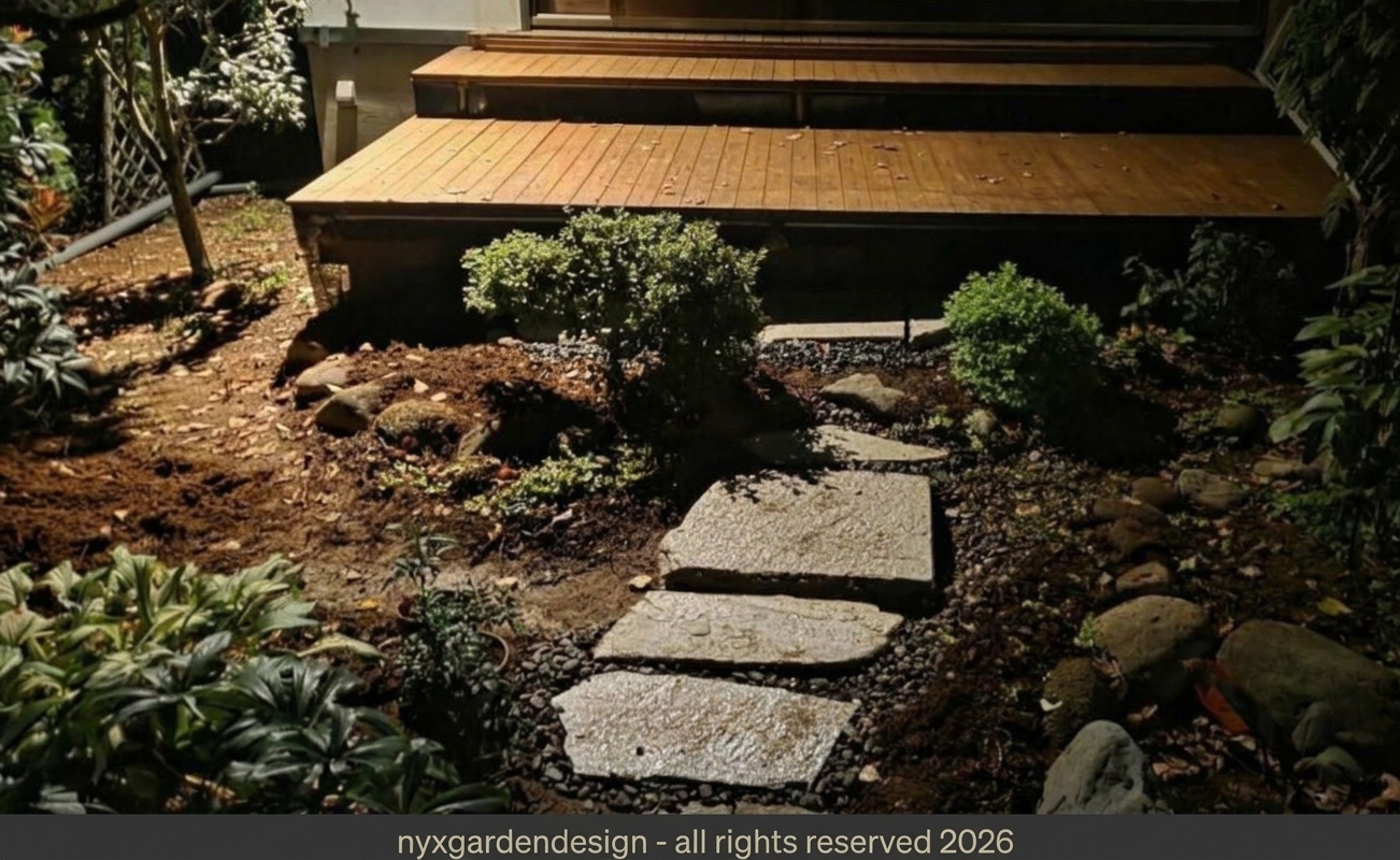 A modern Japanese garden with illuminated stepping stones leading toward a timber deck