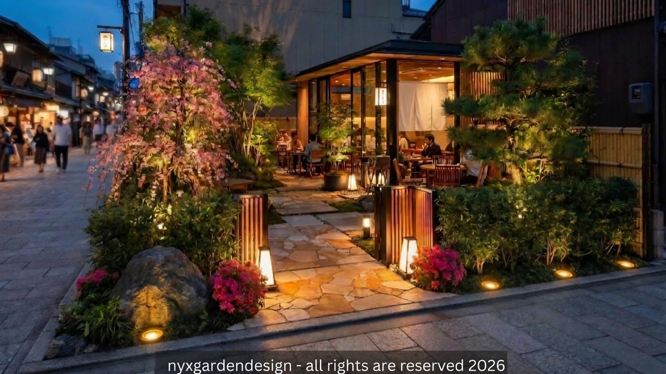 A warmly illuminated modern Japanese garden entrance beside a lively street café at night, with stone paving, layered planting, sculpted pine, and soft garden lighting.